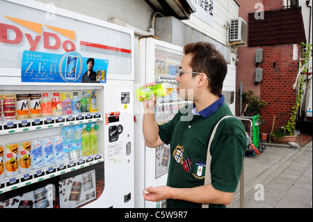 Le Japon, l'homme japonais de boire un rafraîchissement à un distributeur automatique Banque D'Images