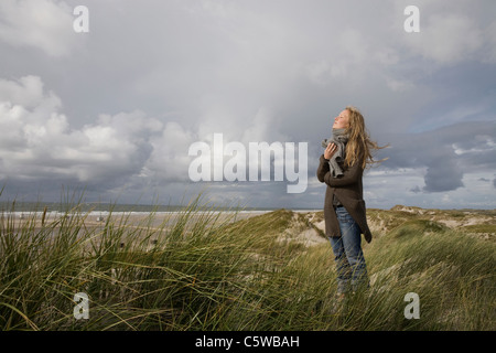 Allemagne, Schleswig Holstein, Amrum, young woman on grassy sand dune Banque D'Images