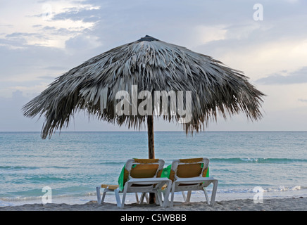 Deux chaises face à un coucher de soleil océan nuageux Banque D'Images