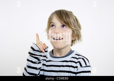 Boy (10-11) pointant vers le haut et à la recherche, portrait Banque D'Images