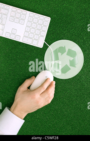 Personne à l'aide de souris, tapis de souris avec symbole de recyclage, elevated view Banque D'Images