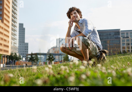 Allemagne, Berlin, Young man using mobile phone, smiling, portrait Banque D'Images