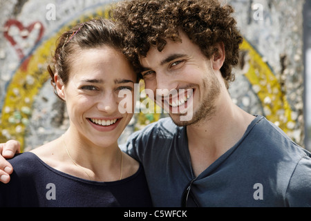 Allemagne, Berlin, young woman standing in front of wall avec graffiti, portrait, close-up Banque D'Images