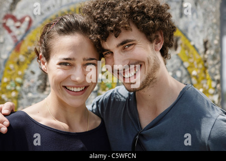 Allemagne, Berlin, young woman standing in front of wall avec graffiti, portrait, close-up Banque D'Images