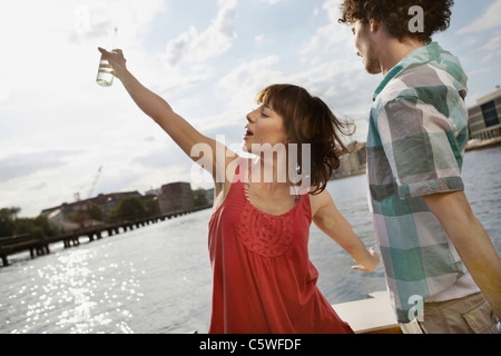 Allemagne, Berlin, Young couple on motor yacht, woman dancing Banque D'Images