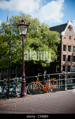 Vélo Orange liés sur Pont sur canal Singel à Amsterdam. Orange est la couleur de la famille royale des Pays-Bas. Banque D'Images