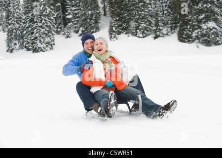 Germany, Berlin, Young couple sledding Down hill, rire, portrait Banque D'Images