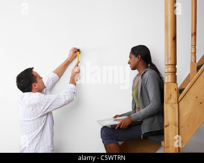 Young couple multiethnique à l'aide d'un marteau pour accrocher des photos sur le mur et sourit. Copy space Banque D'Images