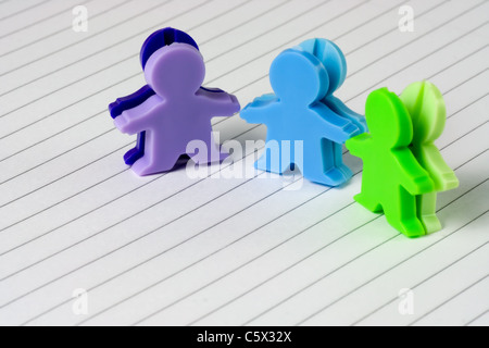 Trois figurines de petits hommes sur un morceau de papier d'écriture Banque D'Images