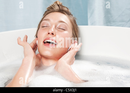 Jeune femme dans une baignoire d'écouter de la musique Banque D'Images