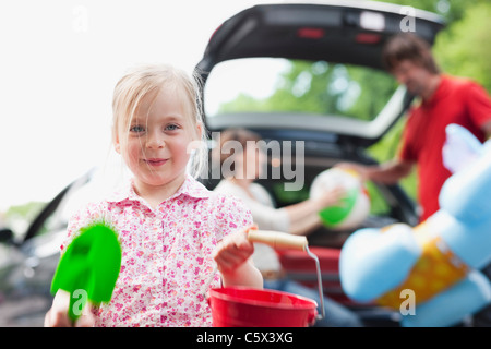 Allemagne, Leipzig, parents charger des bagages en voiture, girl (4-5) en premier plan Banque D'Images