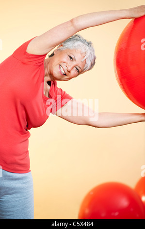 Senior woman pratiquant avec ballon de gymnastique Banque D'Images