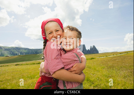 Allemagne, Berlin, Boy (6-7) and girl (8-9) in field, embracing, smiling, portrait Banque D'Images