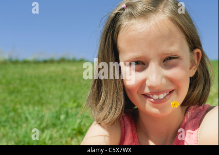 Germany, Berlin, Girl (10-11) avec une fleur dans la bouche, portrait, close-up Banque D'Images