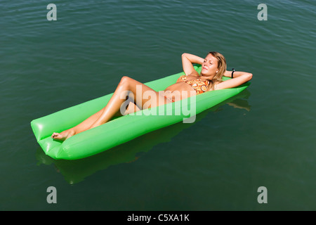 L'Autriche, Salzkammergut, lac de Mondsee, young woman relaxing on matelas Banque D'Images