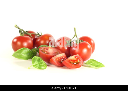 Une poignée de tomates et basilic sur fond blanc Banque D'Images