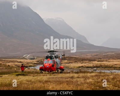 L'équipage de la Marine royale de pilote dirige l'hélicoptère de recherche et de sauvetage pendant qu'il a la tête de Glencoe. Banque D'Images