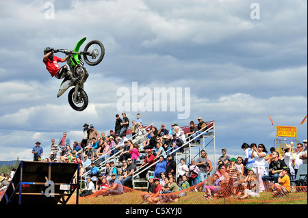 Un moteur cross rider effectue un saut avec une foule de spectateurs à l'arrière-plan. Banque D'Images