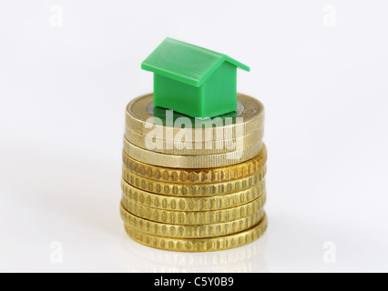 Close-up of a green model house sur une pile de pièces isolated on white Banque D'Images