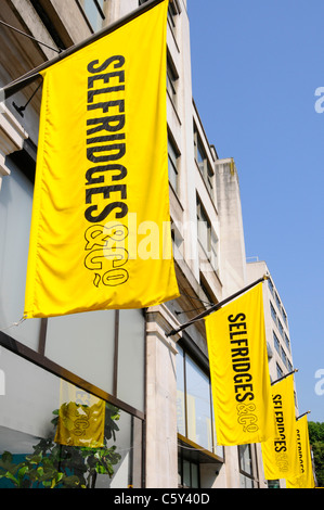 Selfridges & Co Retail Department Retail business shopping store emblématique logo jaune vif bannières bleu ciel soleil jour à West End Londres Angleterre Royaume-Uni Banque D'Images