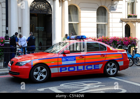 Scène de rue à Londres les policiers du Metropolitan au travail en quête de deux personnes sur la chaussée (visages masqués) À côté de la voiture de police Mayfair Londres Angleterre Royaume-Uni Banque D'Images