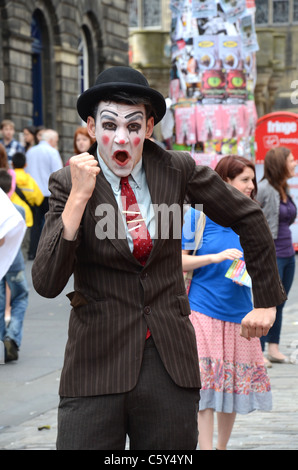 Un acteur dans le maquillage de clown fait la promotion de son émission sur Edinburgh's High Street. Banque D'Images