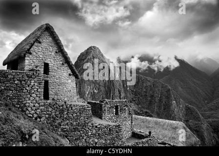 Vue panoramique de Machupicchu très haut dans les Andes péruviennes. Avec cabane en bois et montagnes brumeuses. L'image monochrome. Banque D'Images