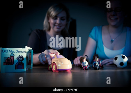 Les jeunes filles et les orthophonistes l'Orthophonie avec accessoires et jouets d'enfants pour la formation à l'avant-plan éclairé Banque D'Images