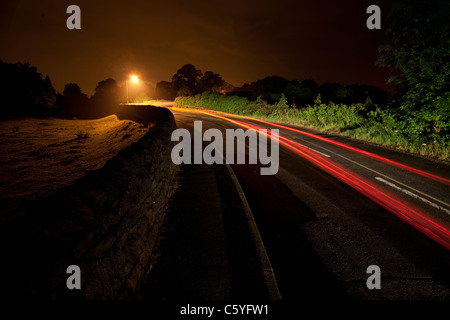 Une longue exposition de voiture la nuit sur une route rurale. Banque D'Images