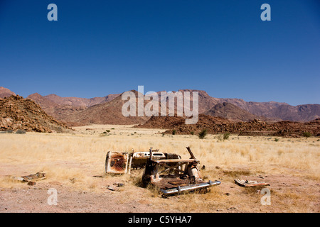 L'épave d'une vieille voiture se trouve en face de la montagne Brandberg. Kaokoveld, Damaraland. La Namibie. Banque D'Images