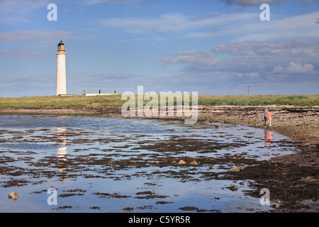 Couple avec promenade de chiens par Barns Ness phare, près de Dunbar, East Lothian, Scotland, UK Banque D'Images