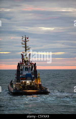 Un remorqueur remorque une barge à l'aide d'un cric pour construire le parc éolien offshore Walney, Cumbria, UK. Banque D'Images