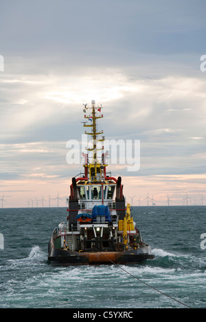 Un remorqueur remorque une barge à l'aide d'un cric pour construire le parc éolien offshore Walney, Cumbria, UK. Banque D'Images