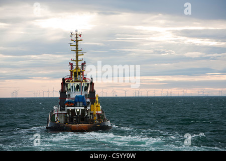 Un remorqueur remorque une barge à l'aide d'un cric pour construire le parc éolien offshore Walney, Cumbria, UK. Banque D'Images