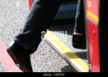 Les jambes d'une personne à bord d'un bus de Londres rouge à un arrêt d'autobus Banque D'Images