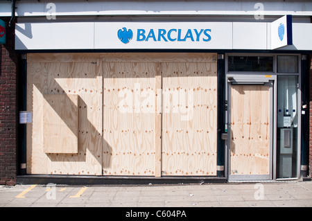 Un homme passe la banque Barclays sur Walthamstow High Street, barricadés après l'émeutes de Londres le 8 août 2011. Banque D'Images