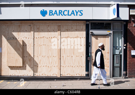 Un homme passe la banque Barclays sur Walthamstow High Street, barricadés après l'émeutes de Londres le 8 août 2011. Banque D'Images