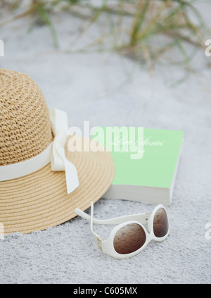 USA, Floride, Saint Pete Beach, chapeau de paille, lunettes de soleil et livre sur beach Banque D'Images