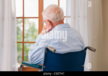 États-unis, Illinois, Metamora, vue arrière du senior man on se reposant en fauteuil roulant à l'avant de la fenêtre Banque D'Images