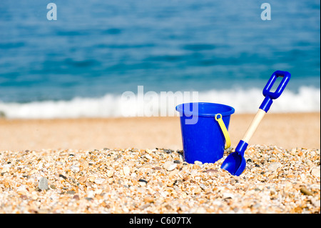 Jouet pour enfants bleu seau et chat sur la plage Banque D'Images