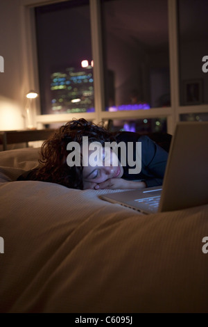 USA, l'État de New York, New York City, jeune femme endormie par laptop on bed Banque D'Images