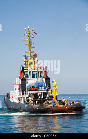 Un remorqueur qui remorque une barge à l'aide d'un cric en place pour construire le parc éolien offshore Walney, Cumbria, UK. Banque D'Images