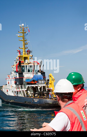 Un remorqueur qui remorque une barge à l'aide d'un cric en place pour construire le parc éolien offshore Walney, Cumbria, UK. Banque D'Images