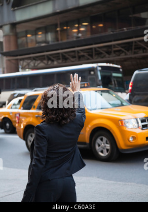 USA, New York, New York City, rear view of woman hailing taxi Banque D'Images