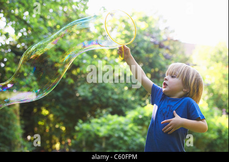 Boy making bulle surdimensionné in backyard Banque D'Images