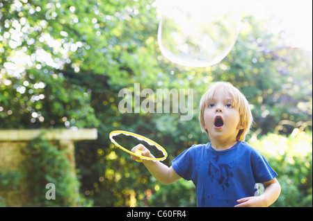 Boy making bulle surdimensionné in backyard Banque D'Images