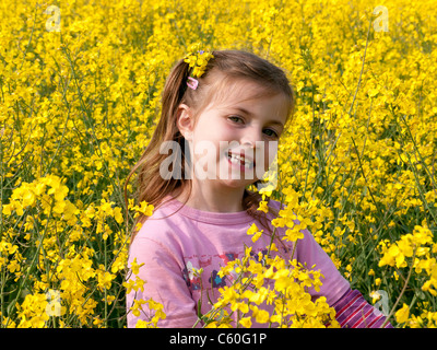 Jeune fille avec une robe rose dans un champ de colza jaune au printemps à Chesham, Buckinghamshire, Royaume-Uni Banque D'Images