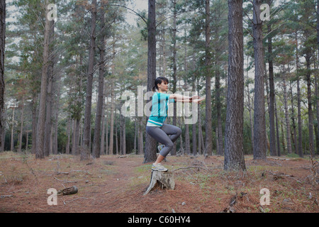 Woman balancing sur moignon en forêt Banque D'Images