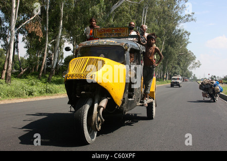 Les passagers s'accrochent au toit d'un monde vintage trois roues Bajaj Tempo bus taxi sur la campagne du Pendjab au nord de l'Inde Banque D'Images