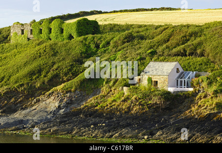 Une vieille ruine couverte de lierre et donnant sur le port à Abercastle, Pembrokeshire, Pays de Galles et le côté d'une petite maison de vacances chalet. Banque D'Images